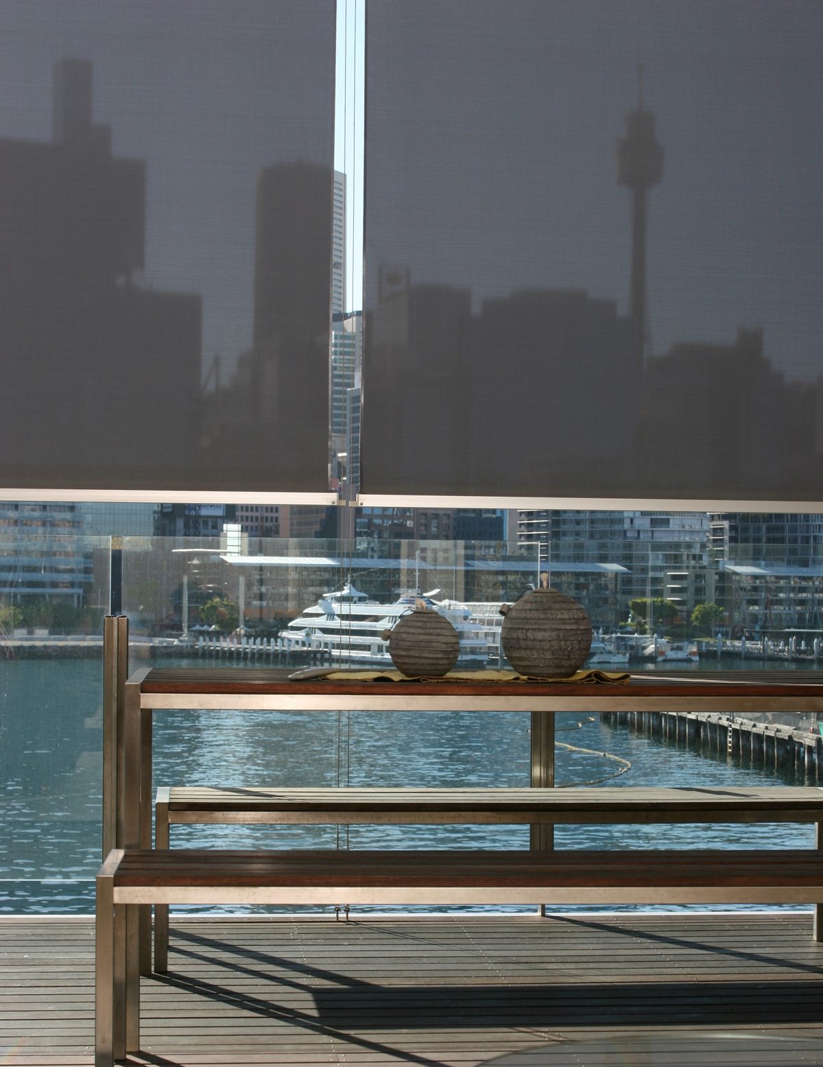 External sunscreen blind lowered over an alfresco deck with a harbour view